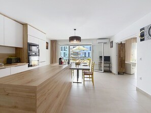 A modern kitchen with a central island, built-in appliances, and a dining area with chairs. - L'Instant Azur, Beach, on foot, Clim Garage (Fréjus)
