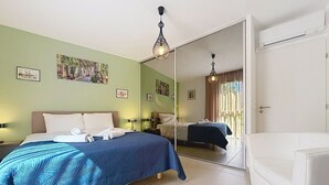 A hotel room with a bed, a chair, a mirror, and artwork on the walls. - L'Instant Azur, Beach, on foot, Clim Garage (Fréjus)