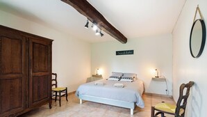 A bedroom with a bed, two bedside tables, a wooden wardrobe, and a mirror on the wall. - Gîtes de France® - The Little House on the Prairie (ANCRETTEVILLE SUR MER)