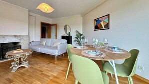 En moderne stue med pejs, spisebord til fire personer og sofa.