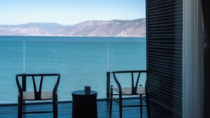 A balcony with two chairs and a small table, overlooking a body of water and distant mountains. - Anye Seaview Hotel Dali (Dali)