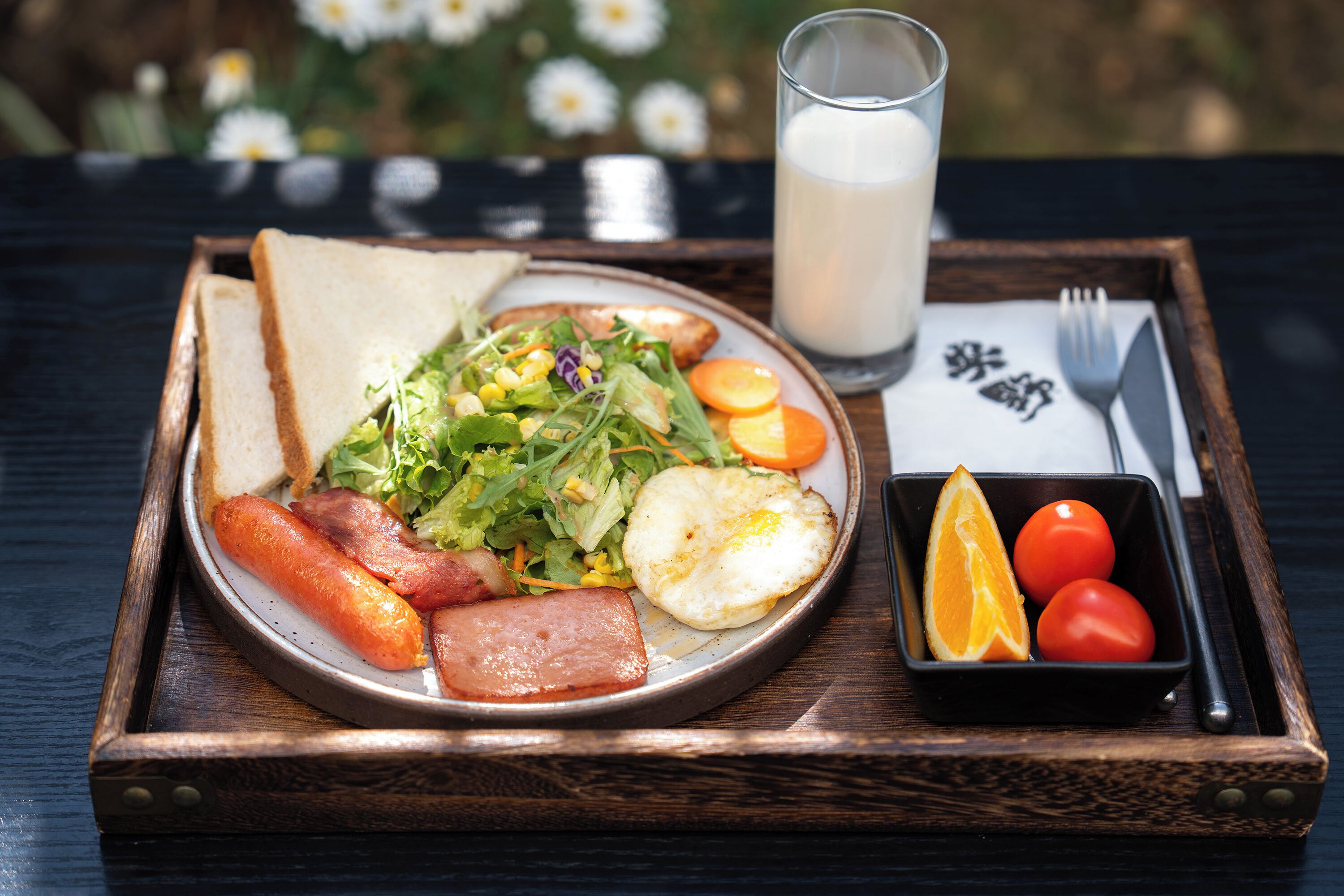 Ein Frühstückswagen mit Toast, Eiern, Speck, einem Salat und einem Glas Milch.