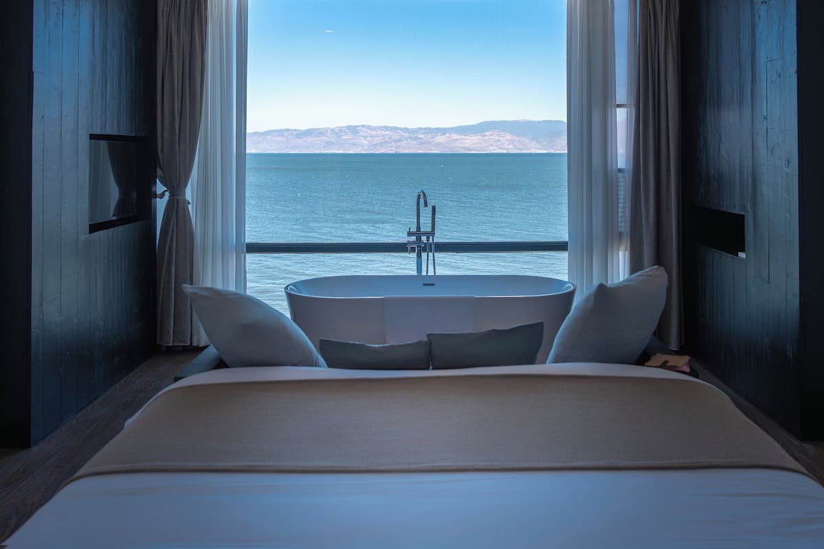 A bedroom with a bed, a round table, and a view of the sea.