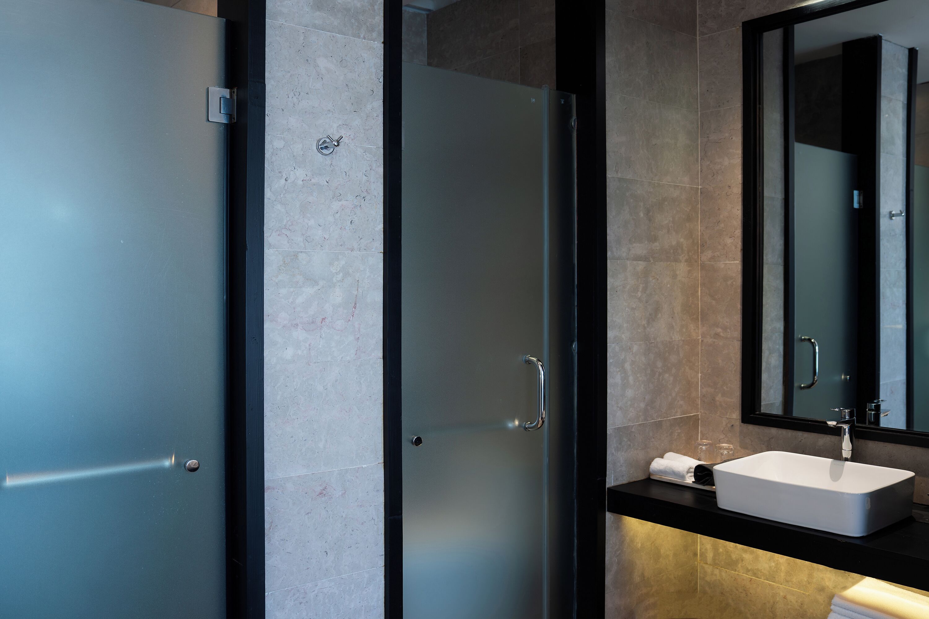 A modern bathroom with a glass shower door, a white sink, and a large mirror.