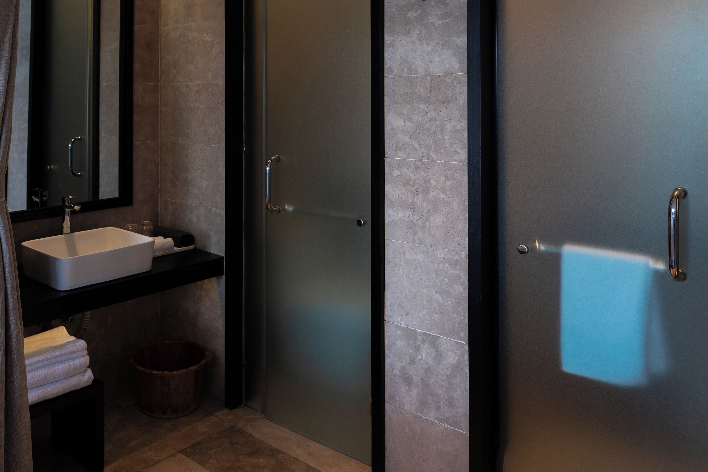 A modern bathroom with a sink, mirror, and a door with a handle.