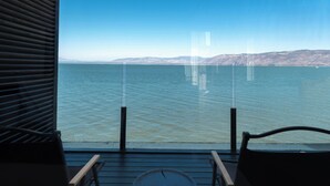 A balcony with two chairs and a small table, overlooking a calm body of water with distant mountains. - Anye Seaview Hotel Dali (Dali)