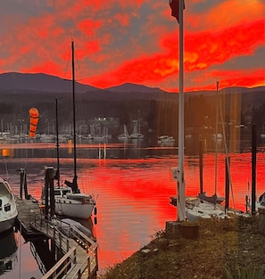 Ein Yachthafen mit vertäuten Booten, einem klaren Himmel und Bergen im Hintergrund.