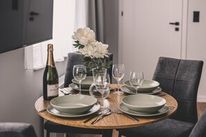 Uma mesa de jantar com pratos, copos, uma garrafa e um vaso de flores.