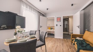 Habitació moderna amb zona de menjador, sofà, televisió i llit.