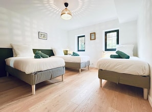 Ein Zimmer mit zwei Betten, einer Deckenleuchte und Fenstern.
