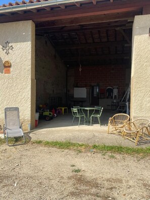 An outdoor patio area with a table and chairs, a folding chair, and a brick wall. - Marcal - Clermont-le-Fort (CLERMONT LE FORT)