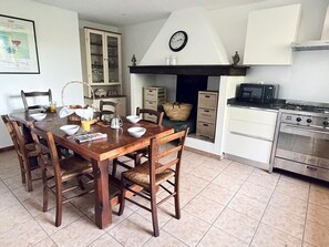 A kitchen with a wooden dining table, chairs, a stove, cabinets, and a clock on the wall. - Marcal - Clermont-le-Fort (CLERMONT LE FORT)