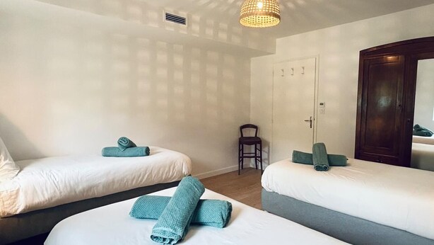 Une chambre d’hôtel avec deux lits, une chaise, une armoire et un luminaire au plafond.