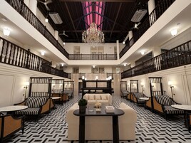 Un hall de hotel espacioso y de varios niveles, con una zona de estar central, techos altos y un candelabro.