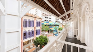 A multi-level building with white railings, a covered walkway, and colorful buildings in the background. - Aura Opera House Chinatown- Newly Renovated (Singapore)