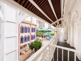 Un edificio de varios niveles con barandales blancos, un paseo techado y edificios coloridos al fondo.