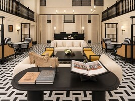 Un vestíbulo de hotel con una zona de estar central, una mesa de centro negra y un sofá.