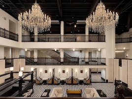 Un hall de hotel de varios niveles con candelabros, una escalera y zonas de estar.