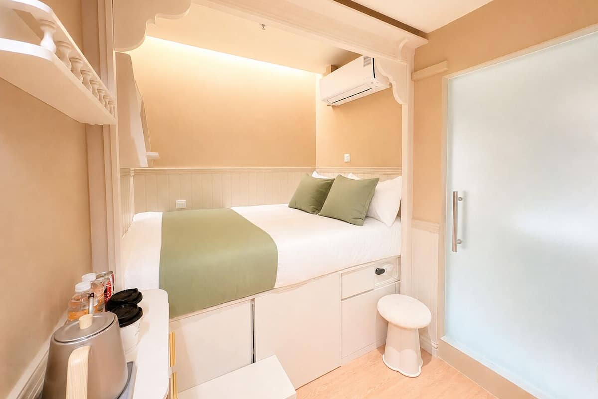 Habitació d'hotel compacta amb llit superposat, un banyet petit i un armari.