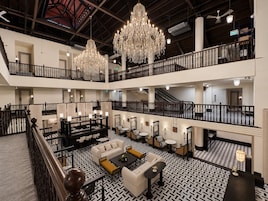 Vestíbulo de hotel de varios niveles con candelabros, una escalera y un piso con diseño.