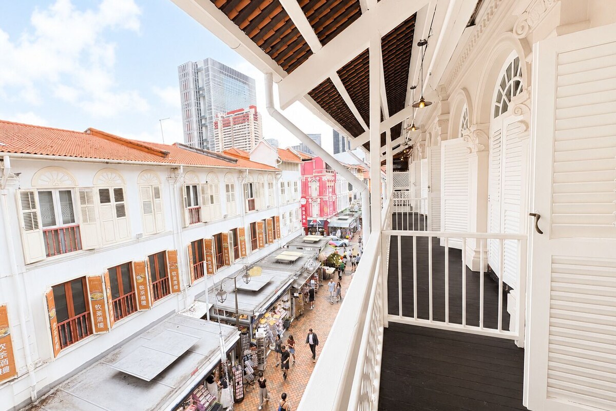 Una calle comercial de varios niveles con arquitectura tradicional, un pasaje cubierto y vistas de edificios modernos al fondo.