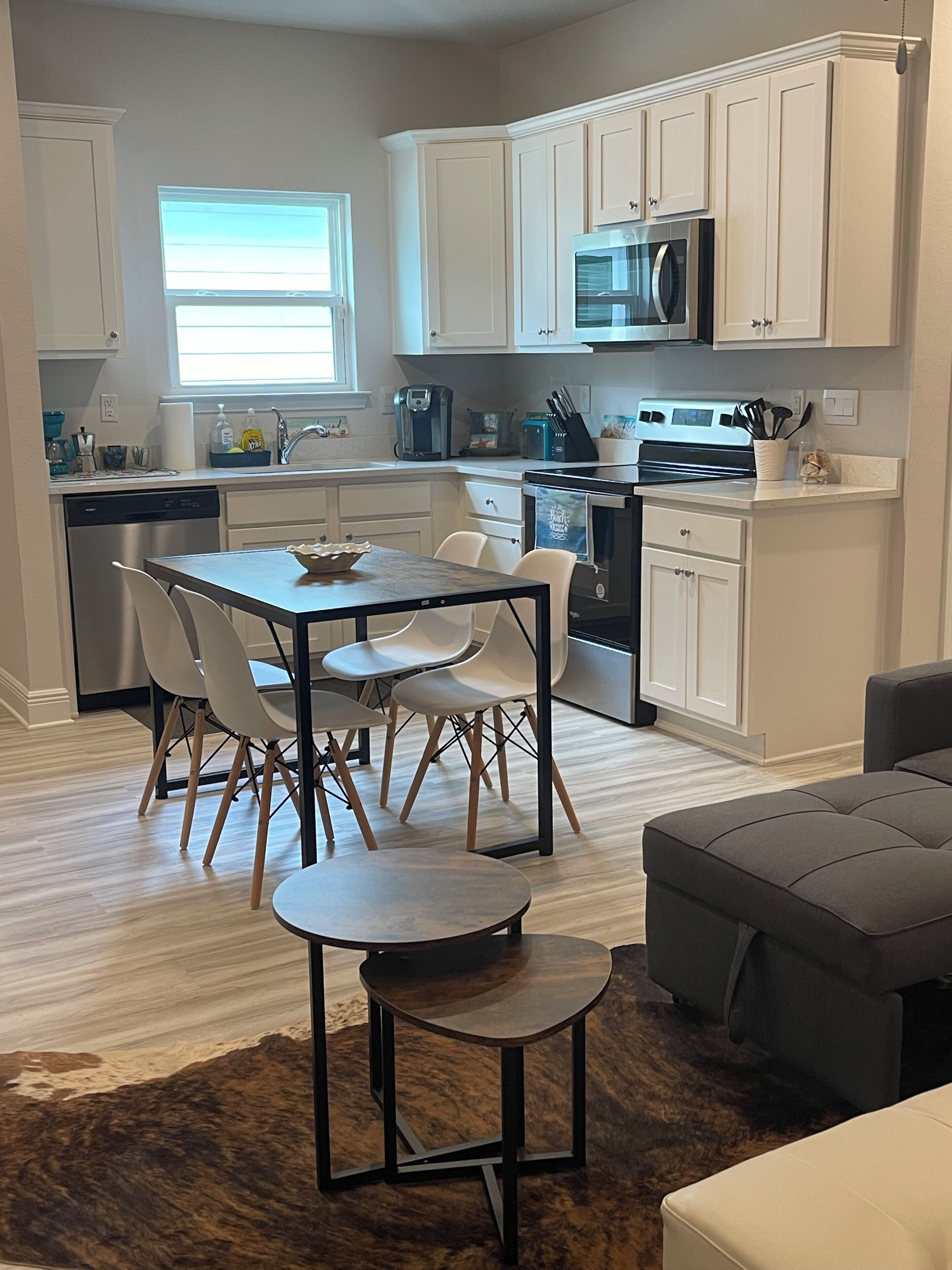 Una cocina moderna con gabinetes blancos, un microondas integrado y un comedor con mesa y sillas.