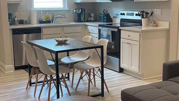 Una cocina moderna con gabinetes blancos, un microondas integrado y un comedor con mesa y sillas.