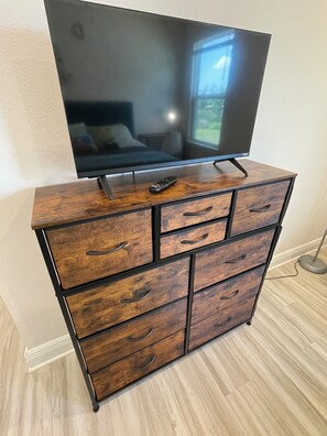 Eine hölzerne Kommode mit Schubladen und ein Flachbildfernseher darauf.