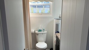 Un baño con inodoro, una ventana con vistas, una cortina de ducha y un dispensador de papel higiénico.