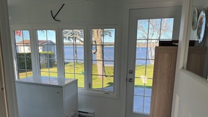 Una habitación con vistas a un lago, un armario blanco y una puerta con paneles de vidrio.