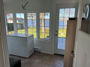 A room with a view of a lake, a white cabinet, and a door with glass panels.