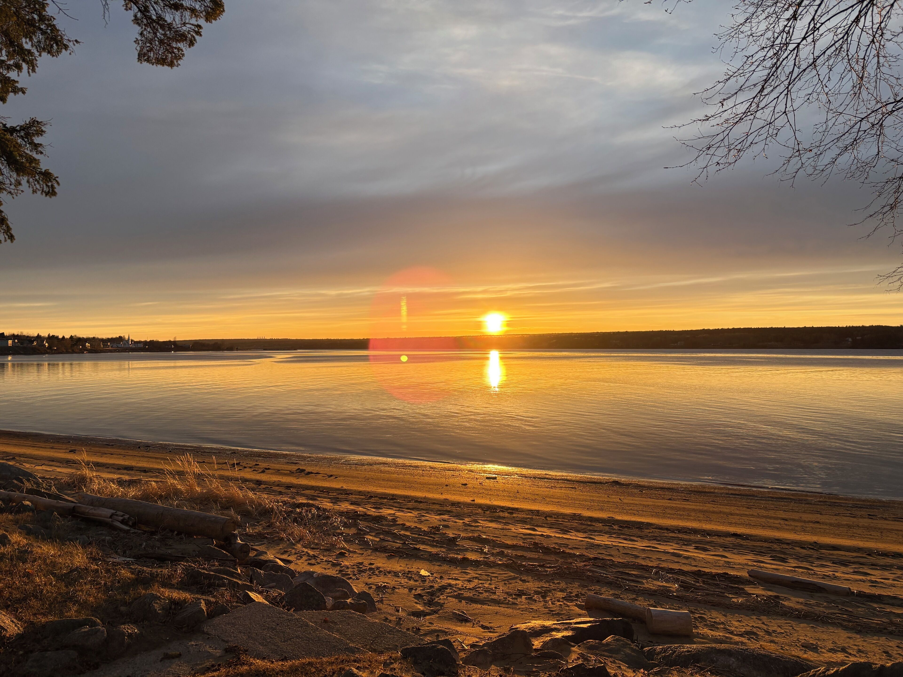 A calm lake at sunset with a distant shoreline.