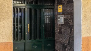 Una entrada de edificio con un letrero que dice 'ATHENA', una puerta de metal, un muro de mármol y un piso de baldosas.