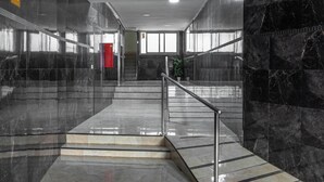 Un interior moderno con una escalera, paredes de mármol y una puerta roja.