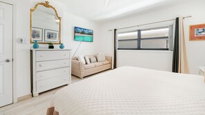 A bedroom with a bed, a dresser, a mirror, a window, and a wall-mounted TV. - Casa Caribe #24 - 3 Bed, 3 Bath - Third Floor Ocean Front Panorama Condo (Seven Mile Beach)