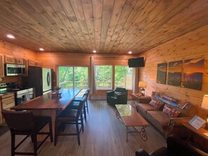 A wooden cabin interior with a kitchen, dining area, and living space.
