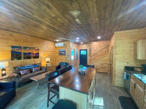A wooden cabin interior with a dining area, sofa, and kitchen.
