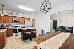 A modern kitchen with wooden cabinets, stainless steel appliances, and a bar area. - Pet Door & Patio, Fort Bliss, North Hills Shopping, Painted Dunes Golf Course (El Paso)