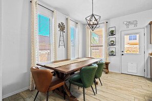 A dining area with a wooden table, leather chairs, and a decorative windmill. - Pet Door & Patio, Fort Bliss, North Hills Shopping, Painted Dunes Golf Course (El Paso)