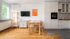 Eine moderne Küche mit weißen Schränken, einem Holzespeisetisch und einem an der Wand befestigten Flachbildfernseher.