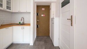 Eine Küche mit weißen Schränken, einer Holztür und einer gefliesten Spritzschutzwand.