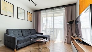 Una sala de estar moderna con un sofá modular, una mesa de centro redonda y un televisor de pantalla plana.
