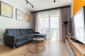 Una sala de estar moderna con un sofá modular, una mesa de centro redonda y un televisor de pantalla plana.