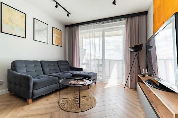 Ein modernes Wohnzimmer mit einem Ecksofa, einem runden Couchtisch und einem Flachbildfernseher.