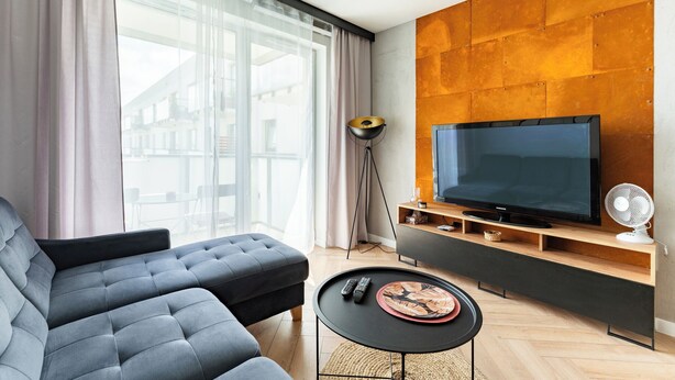 Una sala de estar moderna con un sofá, un televisor, una mesa de centro y una lámpara de pie.