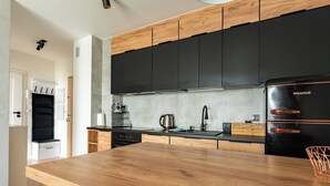 Una cocina moderna con armarios negros, encimera de madera y refrigerador negro.