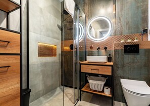 Ein modernes Badezimmer mit einer Duschkabine, einem Waschbecken mit Spiegel und einer Toilette.