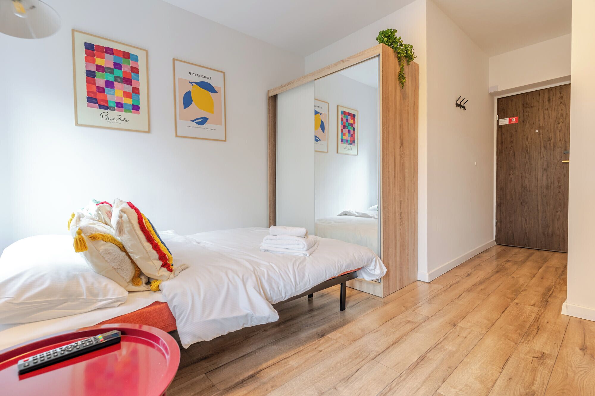 Una habitación de hotel con una cama, una mesita de noche, un espejo y obras de arte en las paredes.