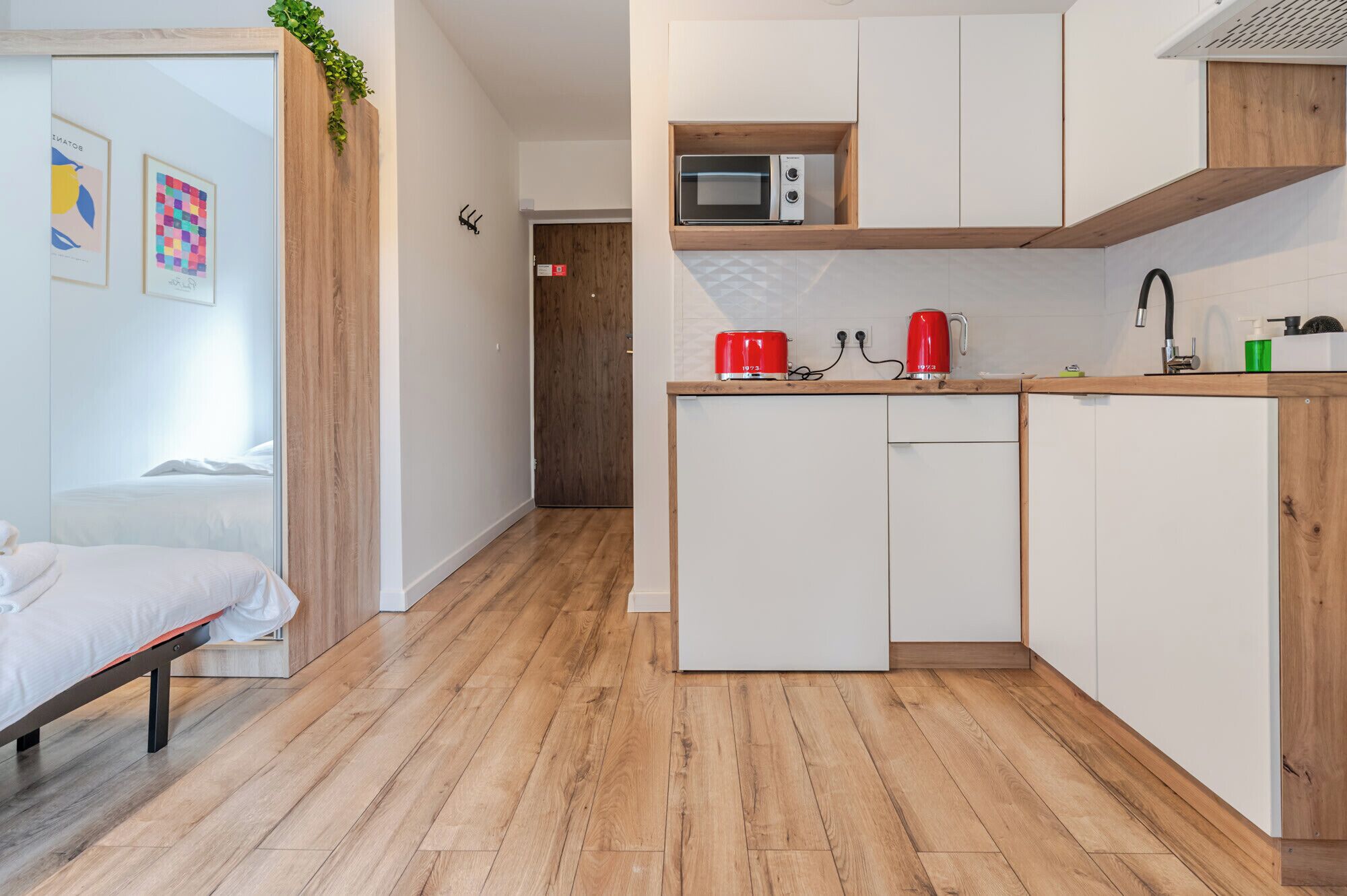 Una cocina moderna con microondas, hervidor rojo y un lavamanos.