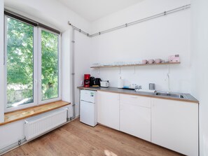 Une petite cuisine avec une fenêtre, une machine à café, une bouilloire et un évier.